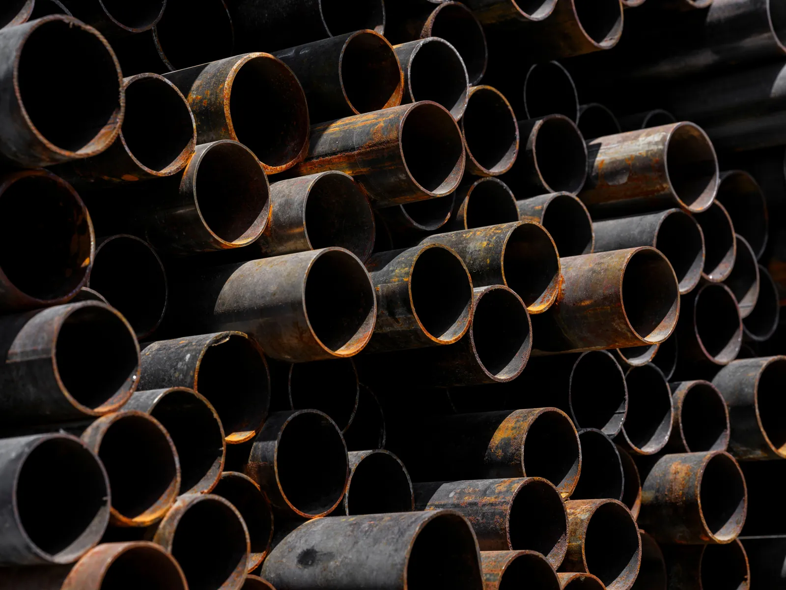 Stacked lengths of heavily rusted iron pipe