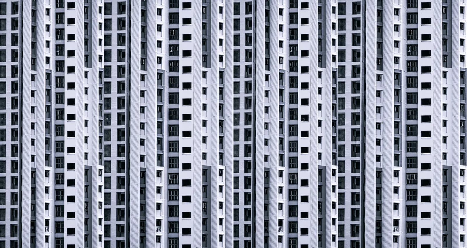 A symmetrical high-rise apartment building facade seen from below