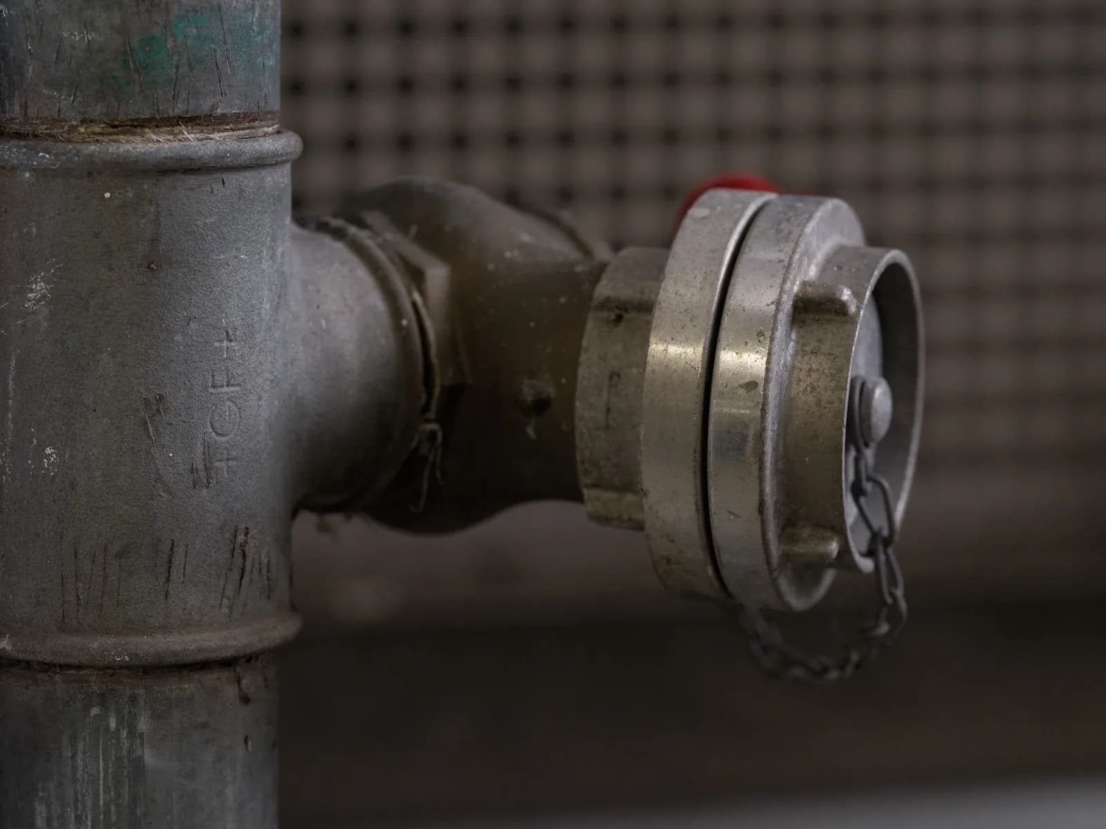 A capped metal pipe fitting with a securing chain