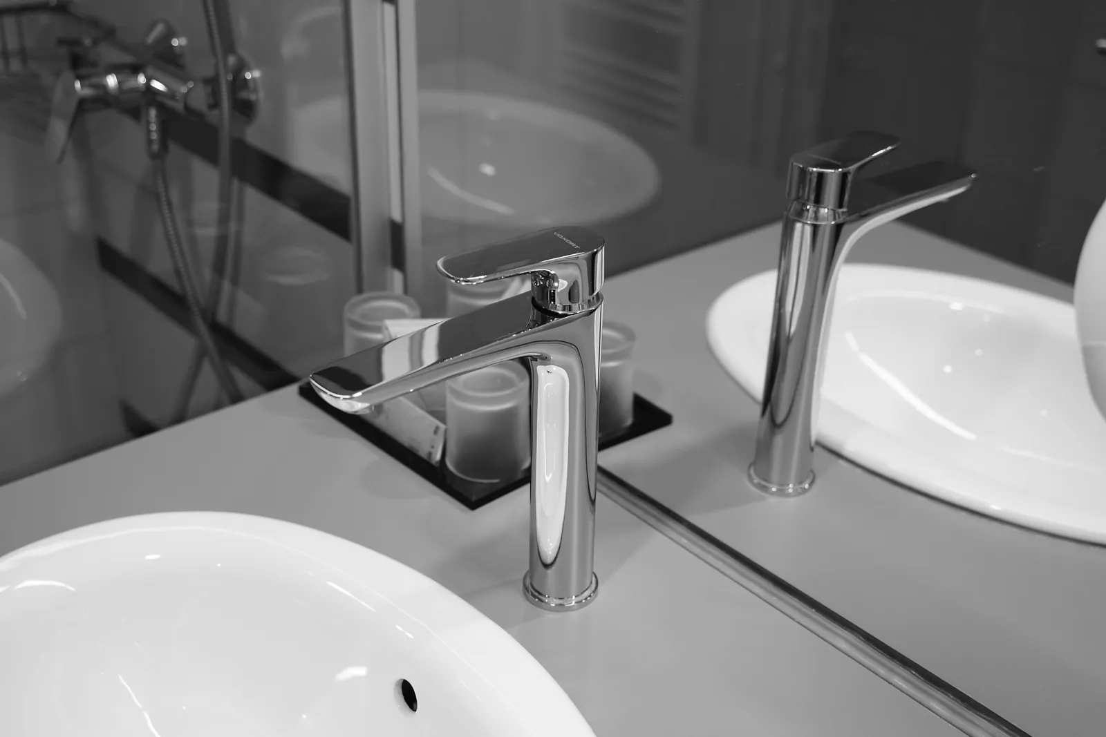 A stainless steel faucet reflected in a bathroom basin