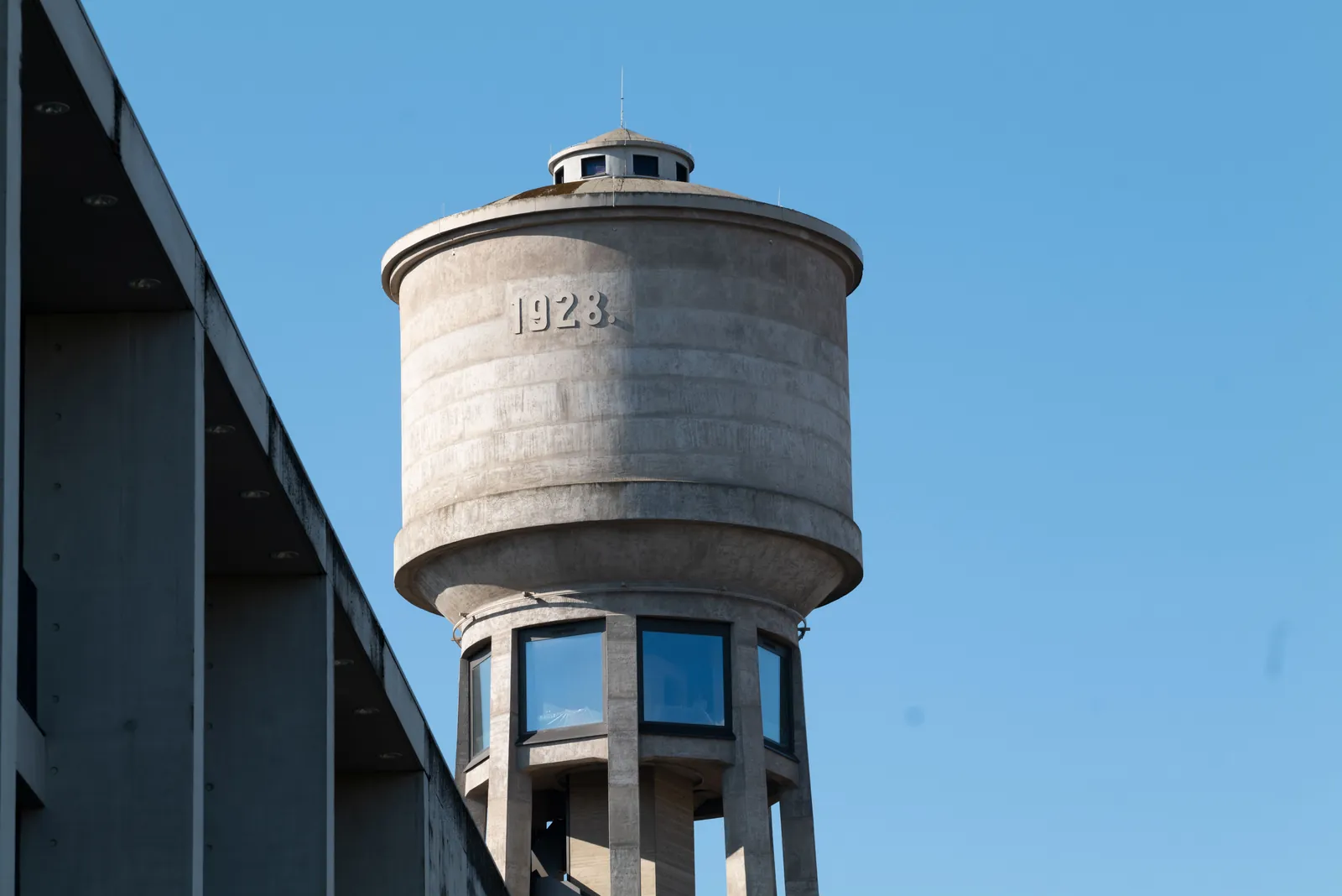 A concrete municipal water tower against a clear blue sky