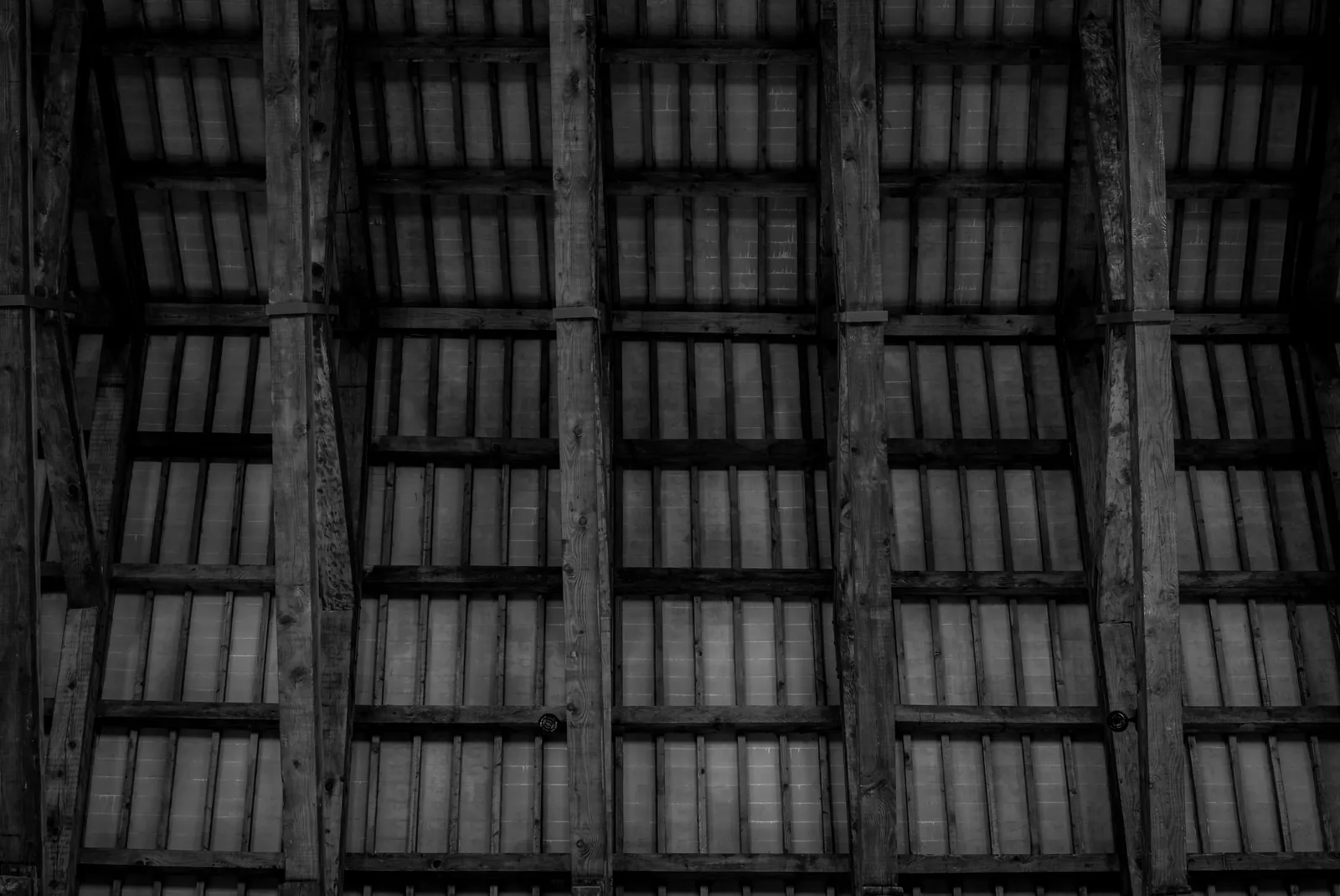 Exposed wooden roof trusses and ceiling timbers in an unfinished attic space