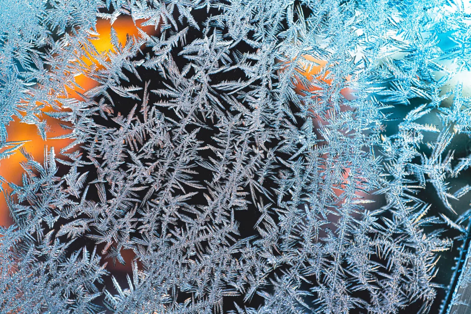 Ice crystals spreading across a window pane on a cold morning