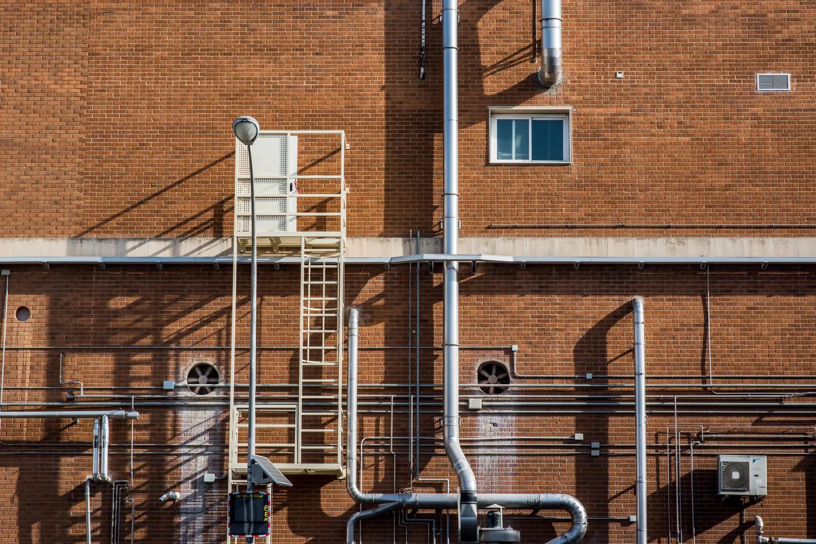 Exposed pipework running across a brick wall