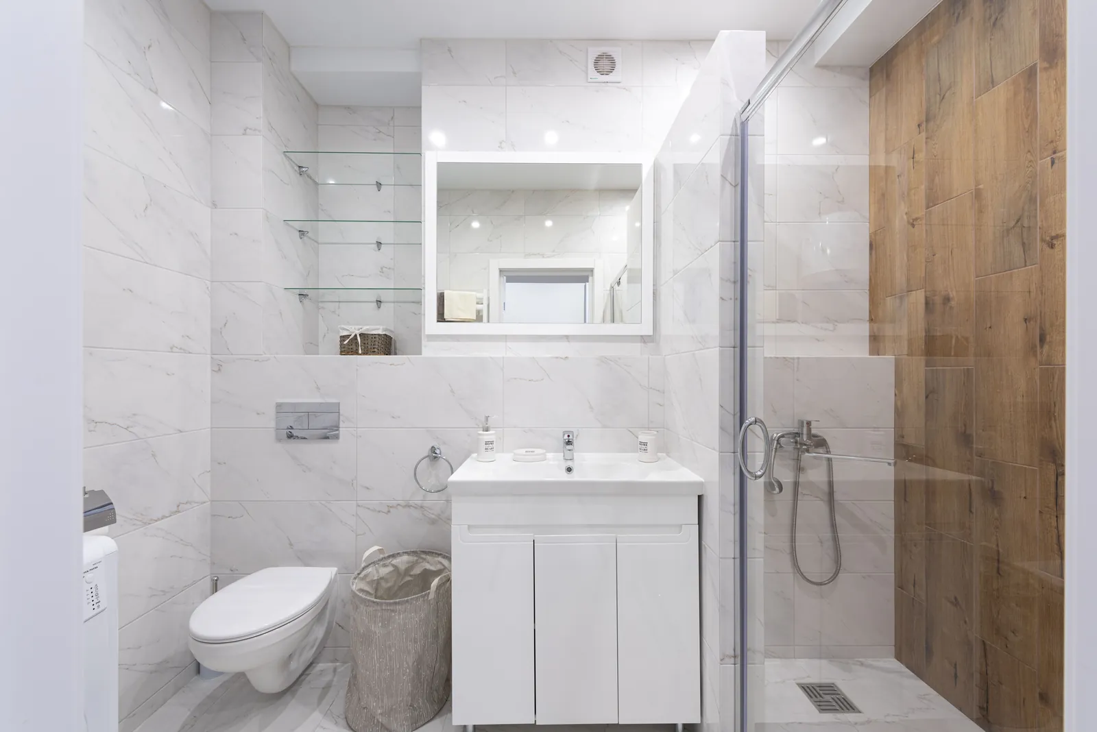 A white toilet beside a tiled bathroom wall in daylight