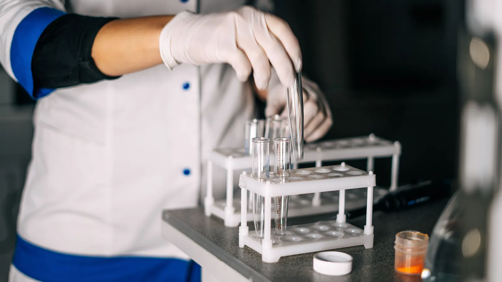 A technician in a lab coat handling sample tubes
