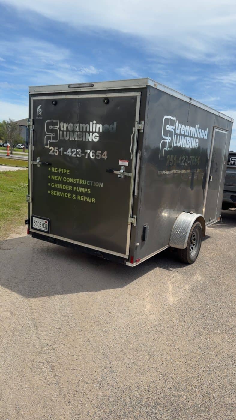 Branded Streamlined Plumbing enclosed trailer lettered with re-pipe, new construction, grinder pump, and service work.